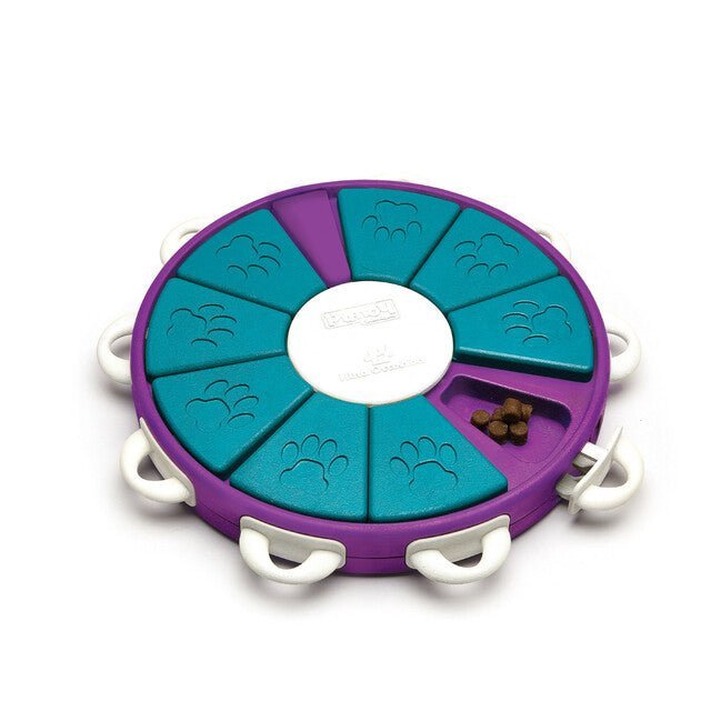 A round dog treat puzzle with nine slots used to hide dog treats. The slots are covered with a lid that can be locked.